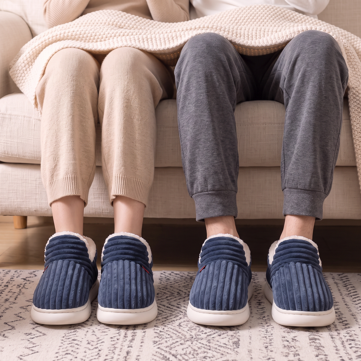 Coffret Duo Elle + Lui : chaussons Cocon Bleu marine assortis portés par un couple sur le canapé